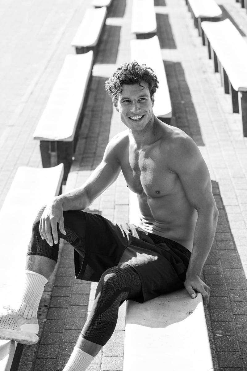 Coach is sitting posing for a photo topless.