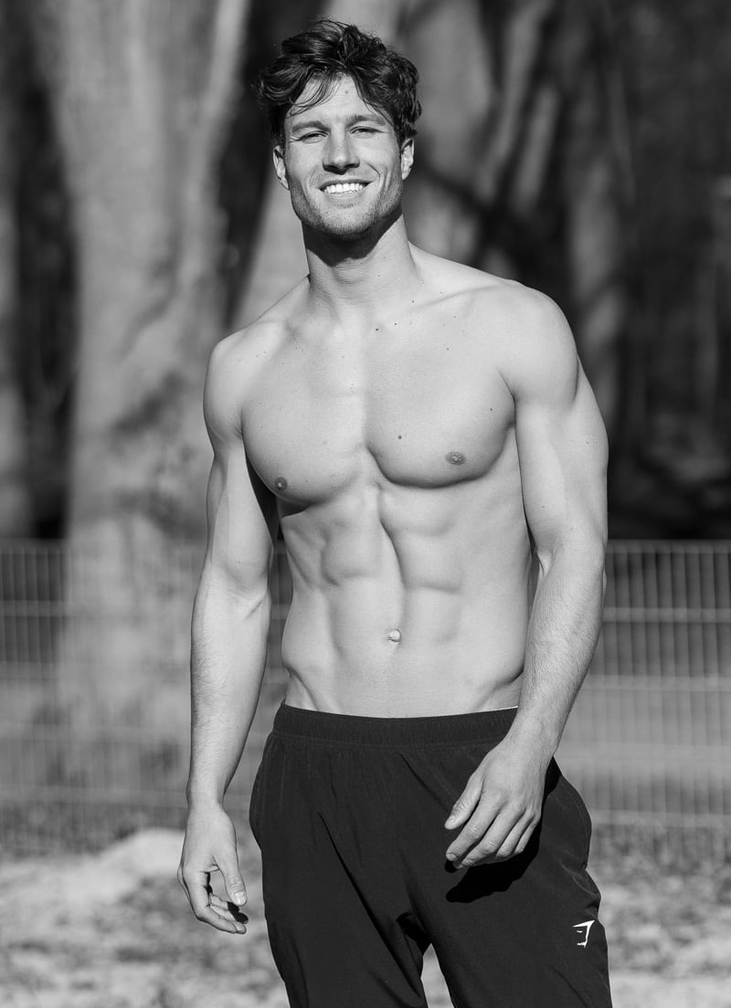 Coach is posing outdoors topless.